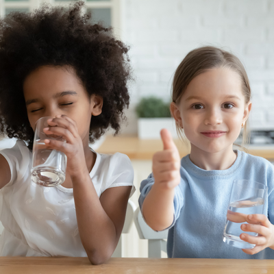 una foto di due bambine che bevono un bicchiere d'acqua