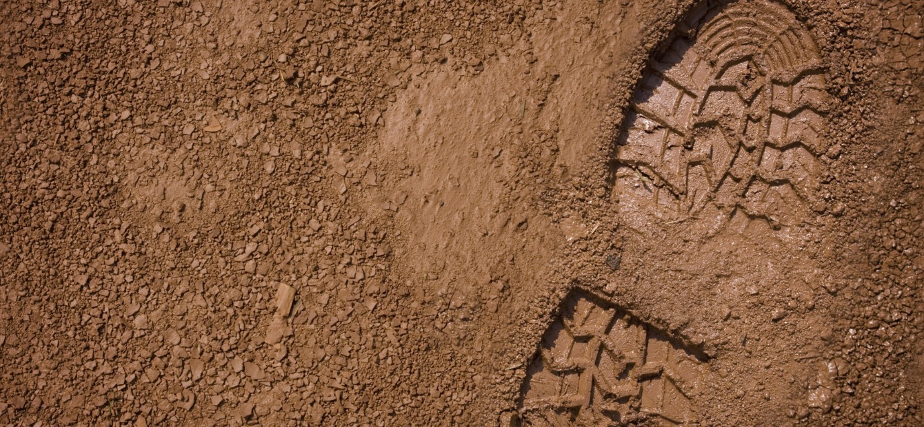 una foto dall'alto di un terreno fangoso con un'impronta di una scarpa sulla parte destra