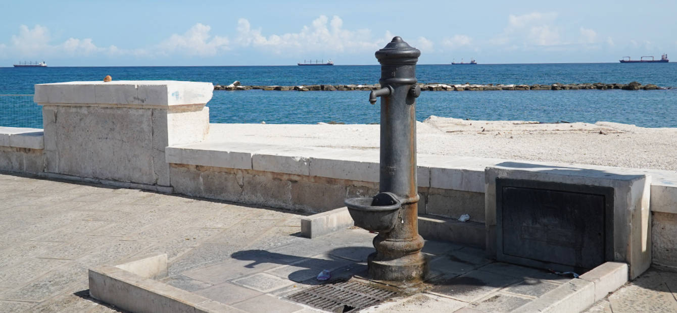 foto del lungo mare di bari con in primo piano una fontana di acquedotto pugliese 