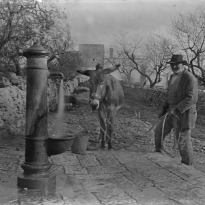 Una fotografia d'epoca in bianco e nero ambientata in una strada di campagna o in un villaggio rurale.